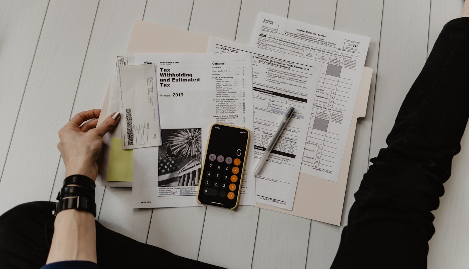 A property manager carefully reviewing a stack of rental application documents at a desk.